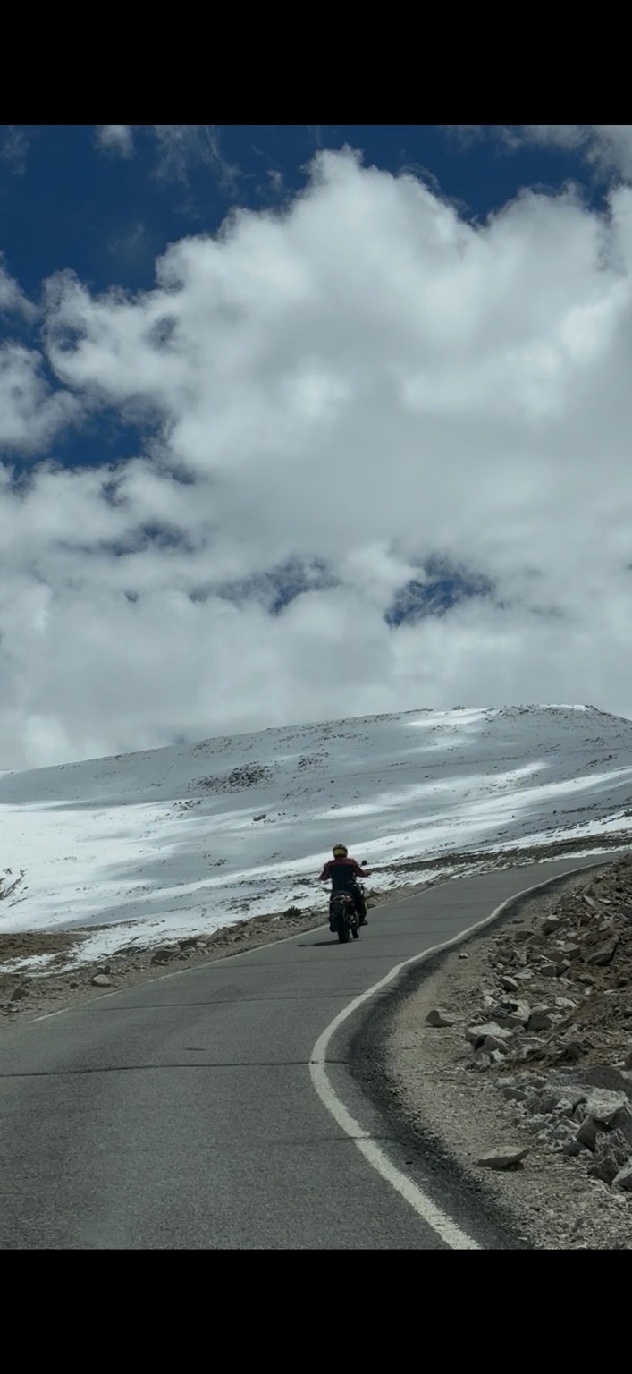 Motorcycle on a winding snow-lined Ladakh road